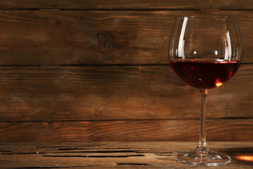 Goblet of red wine on wooden table on wooden wall background