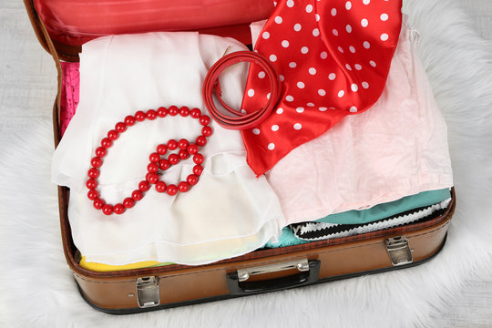 Female clothes in old suitcase on light background