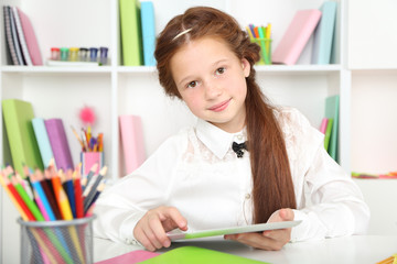 Cute girl with tablet at workplace in classroom