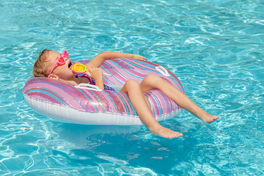 little girl with lollipop lying on the  inflatable rubber circle