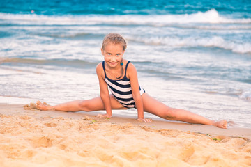 Beautiful little girl excercising on the beach
