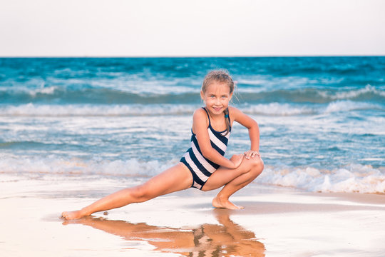 Beautiful little girl excercising on the beach