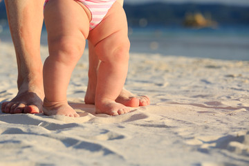 Mother and baby walking on sand beach