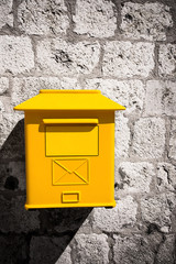 Yellow mailbox on stone wall