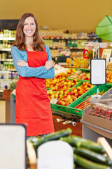 Lächelnde Verkäuferin steht im Supermarkt