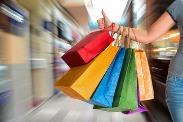 Woman showing thumb up and holding shopping bags