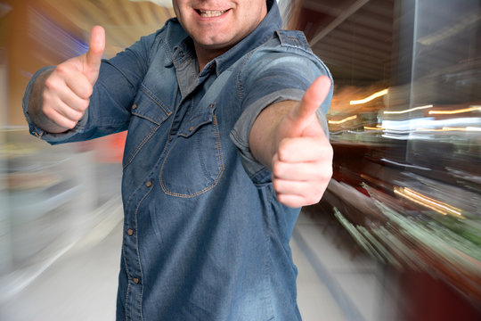 Young man gesturing thumbs up at shopping mall