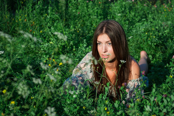 Naklejka na ściany i meble Nice girl among green grass and flowers