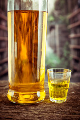 Bottle and glass shot with yellow liqour resembling whiskey, rum