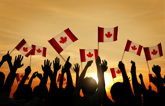 Group of People Waving Flag of Canada in Back Lit