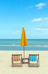 Two beach chairs with sun umbrella on beautiful beach.