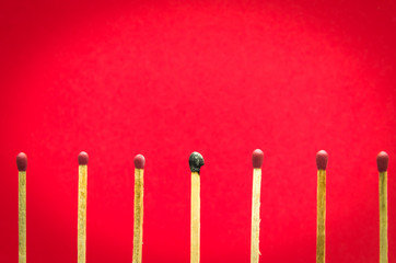 burned match setting on red background for ideas and inspiration