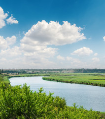 blue sky with white clouds over river in green riverside