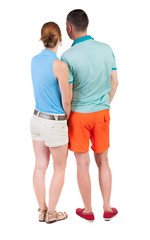 Back view of young embracing couple in shorts  hug and look.