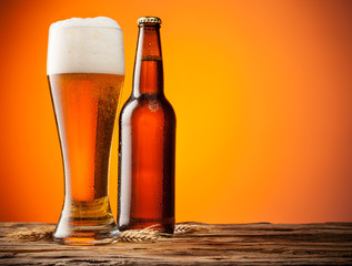 Glass and bottle of beer with orange background