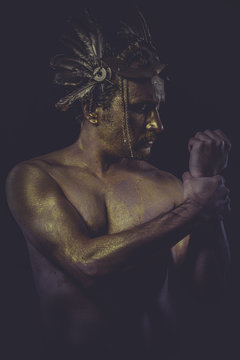 painted golden bodypaint, man with gold helmet, ancient warrior