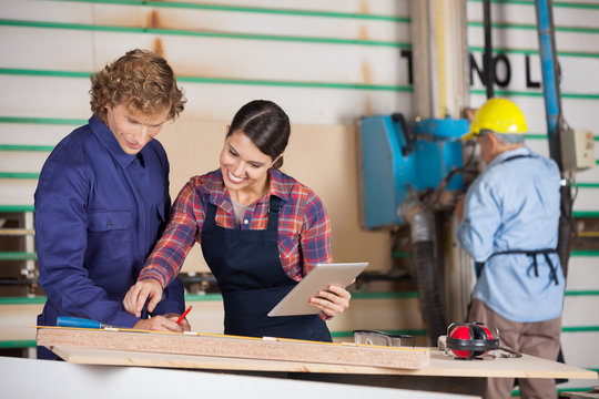Carpenters With Digital Tablet Communicating In Workshop