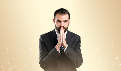 Young businessman pleading over ocher background