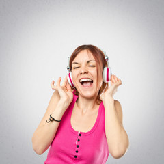 Fototapeta premium Young girl listening music over grey background