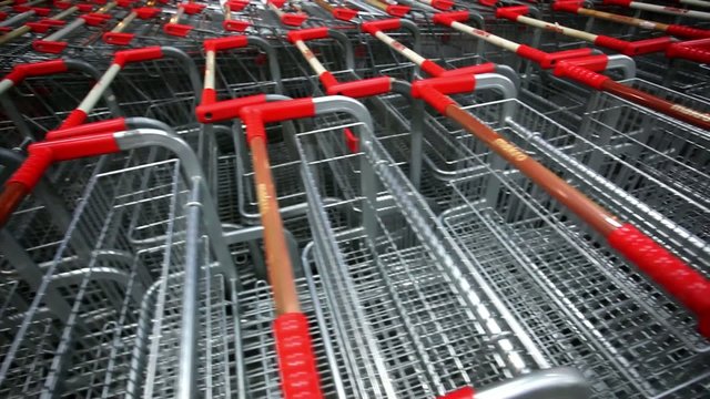 Many empty shopping carts in a row at parking of supermarket on