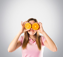 Girl with oranges in her eyes over grey background