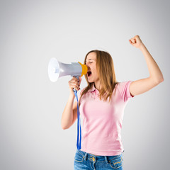 Blonde girl shouting with a megaphone over grey background