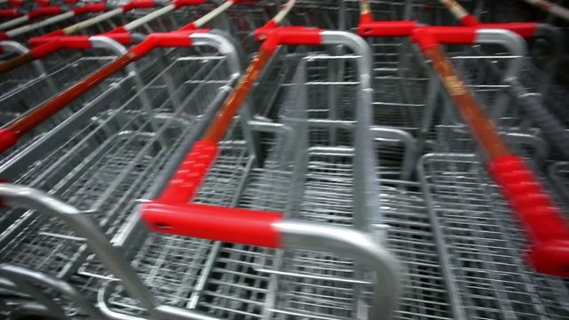 Many empty shopping carts in a row at parking of supermarket on