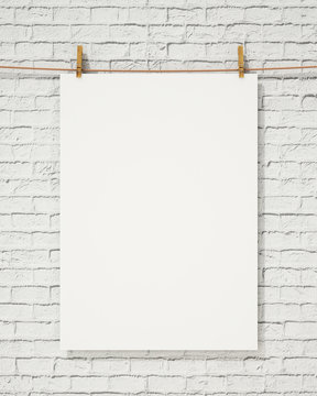 blank white hanging poster with clothespin on brick wall