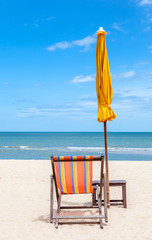 Colorful beach chair and closed umbrella on beautiful beach with