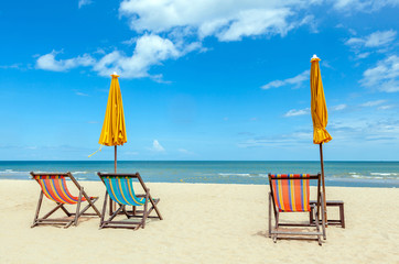 Three beach chairs with sun umbrella on beautiful beach with clo