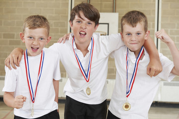 Male School Sports Team In Gym With Medals