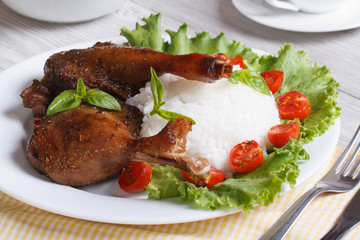 roasted duck leg with rice and salad on the plate horizontal