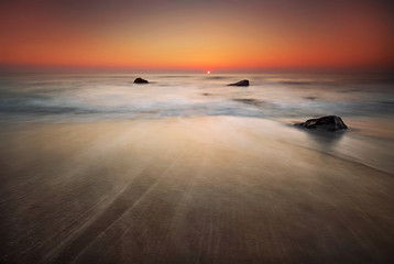 Stormy sea beach with slow shutter and waves flowing out