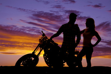Fototapeta na wymiar silhouette couple stand by motorcycle
