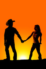 A silhouette of a man and woman holding hands outdoors.