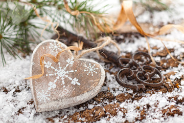 Wooden heart and key on winter background.