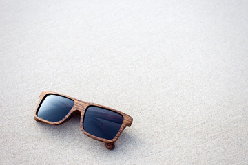 Fototapeta na wymiar wooden sunglasses lying on the sand