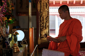 Young Buddhist Monk light incense sticks