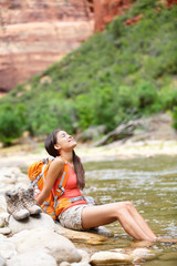 Relaxing hiker woman resting feet in river hiking