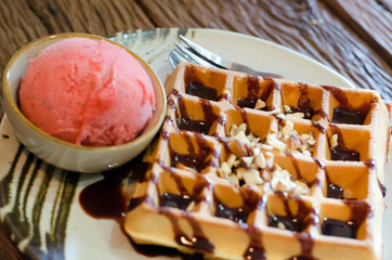 Tasty waffle with scoop of strawberry sherbet ice cream