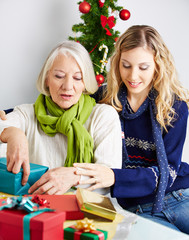 Frau hilft Seniorin beim Verpacken von Geschenken