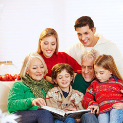 Familie in drei Generationen liest Buch zu Weihnachten