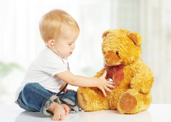 baby plays in doctor toy teddy bear and stethoscope