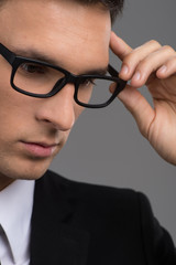 man wearing black glasses on grey background.