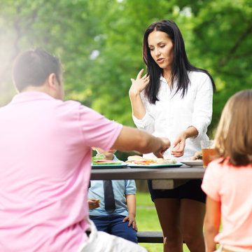 Family Of Four Eating At Barbecue Cookout