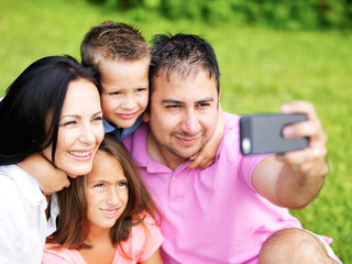 family taking selfies with smartphone in park