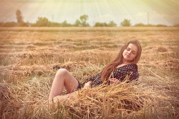 Naklejka na ściany i meble beautiful young brunette girl on the meadow