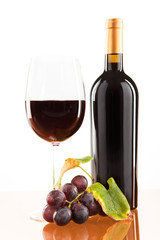 Rotwein im Glas mit Flasche und Weintrauben
