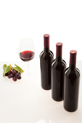 Rotwein im Glas mit Frucht, Blätter und Weinflasche