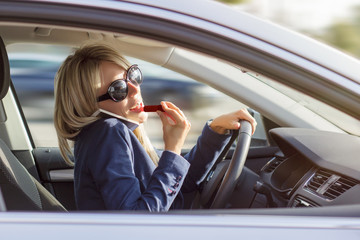 Busy woman talks on phone and does makeup while driving a car - Powered by Adobe